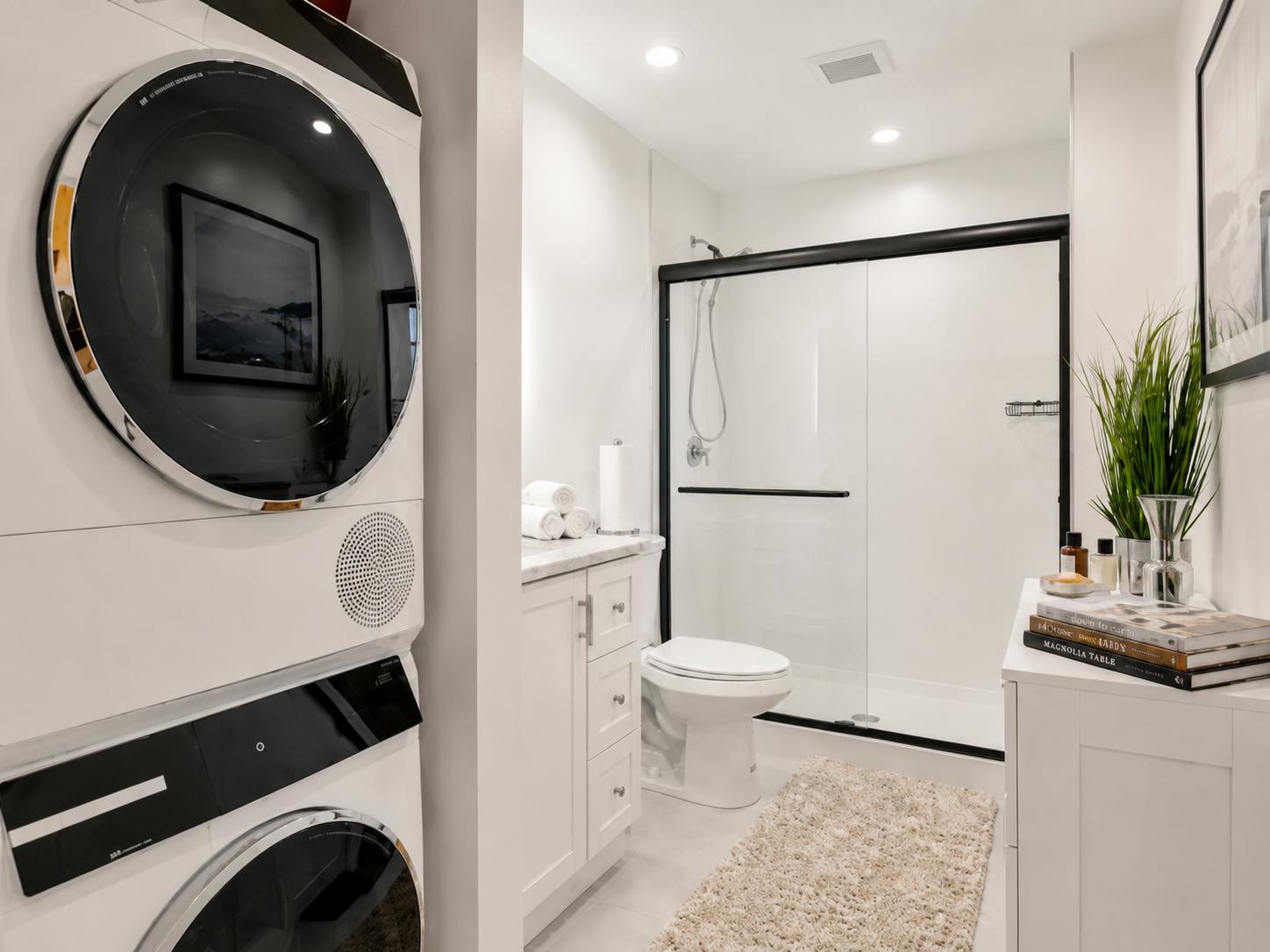 Stacked washer and dryer beside the bathroom with a glass shower at Casa Amaris