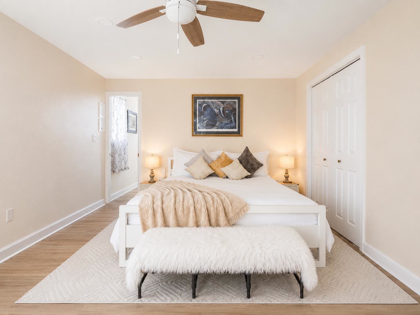 King bedroom at Casa Amaris with white linens, bedside lamps, and a fur bench