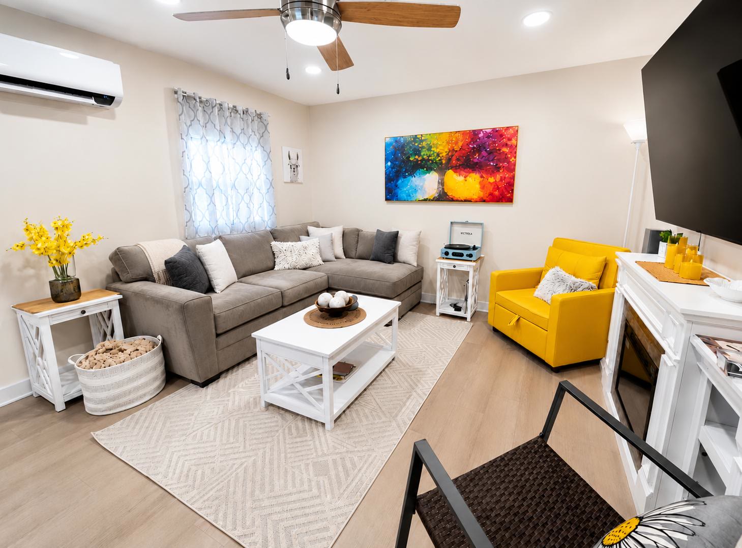 Living room at Casa Amaris with a gray sectional, yellow armchair, and ceiling fan