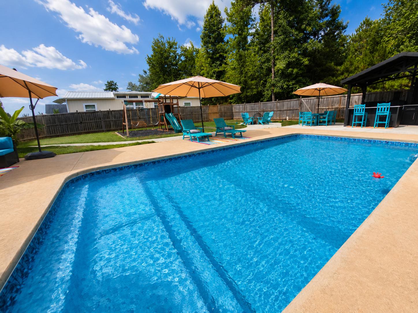 Private rectangular pool at Casa Amaris with teal lounge chairs and patio umbrellas